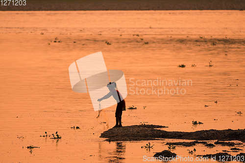 Image of Asian Woman fishing in the river, silhouette at sunset