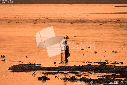 Image of Asian Woman fishing in the river, silhouette at sunset