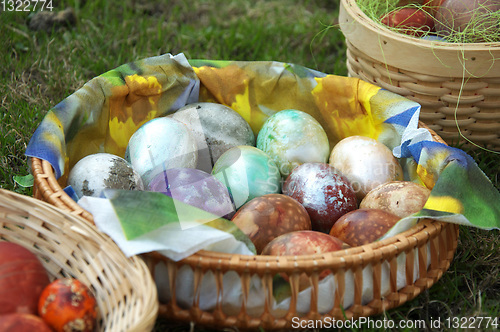 Image of  Speckled eggs in basket on grass.