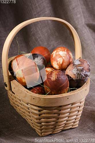 Image of Speckled eggs in basket on brown background.