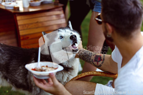 Image of Young man and his dog at barbecue dinner on sunset time