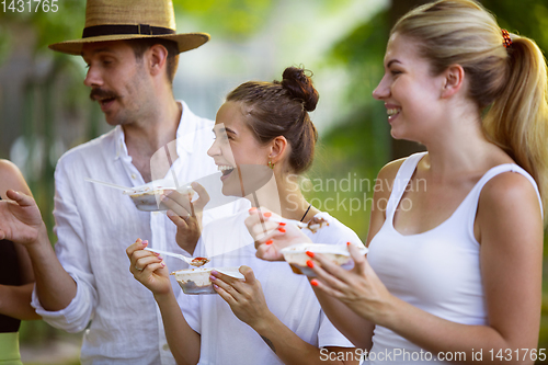 Image of Happy friends eating at barbecue dinner on sunset time