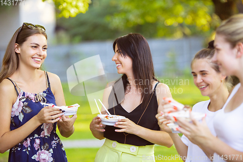 Image of Happy friends eating at barbecue dinner on sunset time