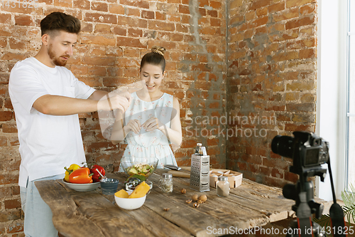 Image of Young couple cooking and recording live video for vlog and social media