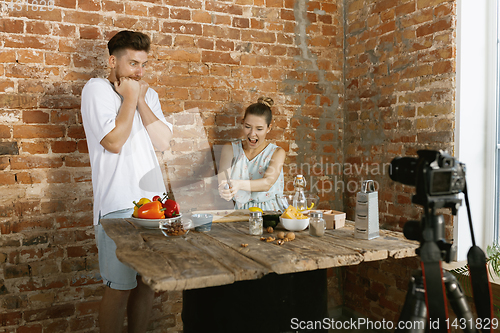 Image of Young couple cooking and recording live video for vlog and social media