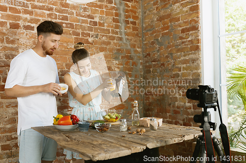 Image of Young couple cooking and recording live video for vlog and social media