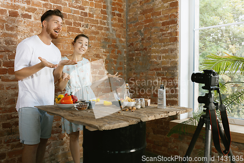 Image of Young couple cooking and recording live video for vlog and social media