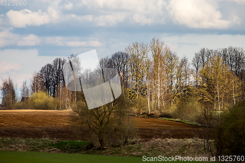 Image of Landscape with plowed field, trees and blue sky