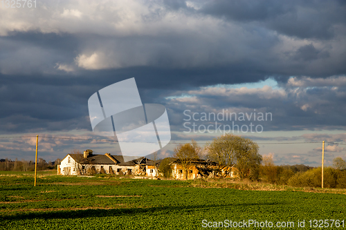 Image of Landscape with cereal field, old farm house and blue sky.