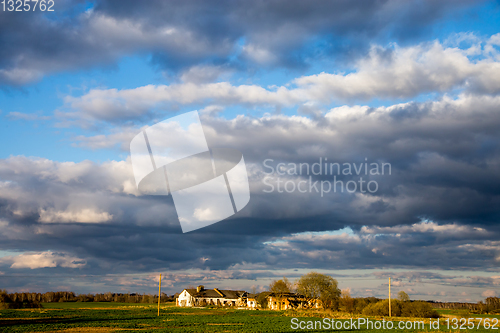 Image of Landscape with cereal field, old farm house and blue sky.