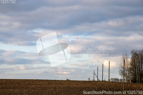 Image of Landscape with plowed field, trees and blue sky