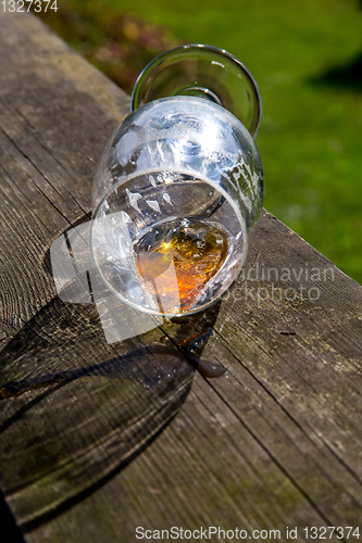 Image of Overturned glass of beer on wooden table.