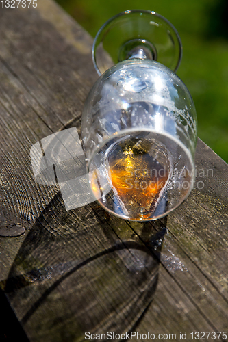 Image of Overturned glass of beer on wooden table.