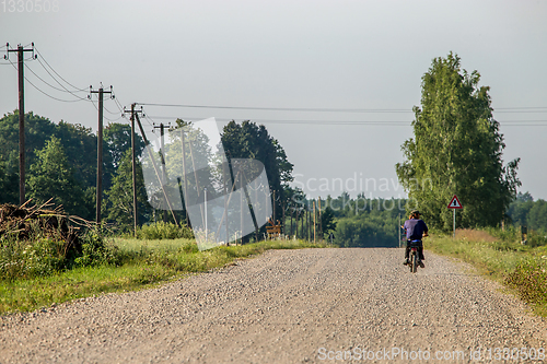 Image of Landscape with rural road and man on moped..