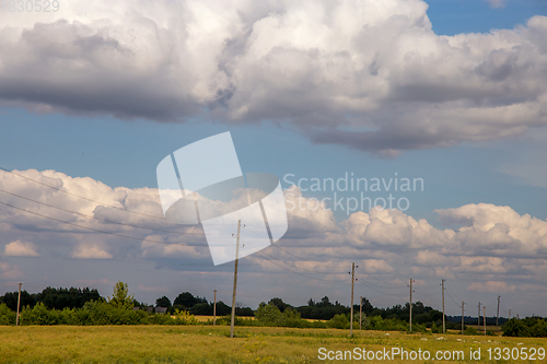 Image of Landscape with cereal field, trees and cloudy blue sky