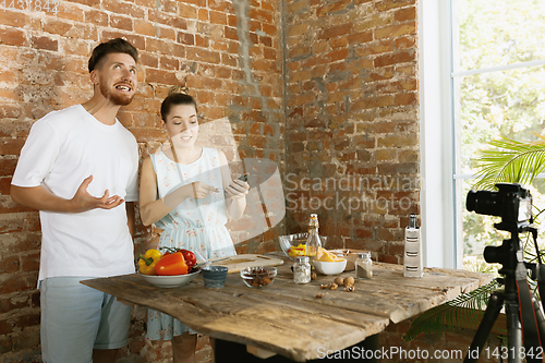 Image of Young couple cooking and recording live video for vlog and social media
