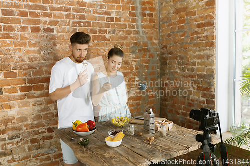 Image of Young couple cooking and recording live video for vlog and social media