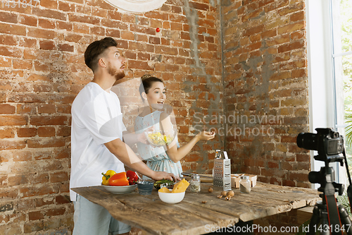 Image of Young couple cooking and recording live video for vlog and social media