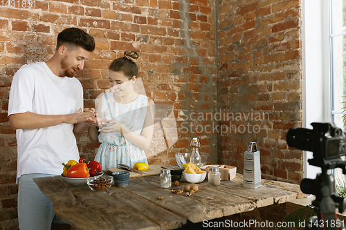Image of Young couple cooking and recording live video for vlog and social media