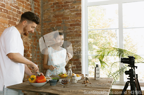 Image of Young couple cooking and recording live video for vlog and social media