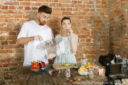 Image of Young couple cooking and recording live video for vlog and social media