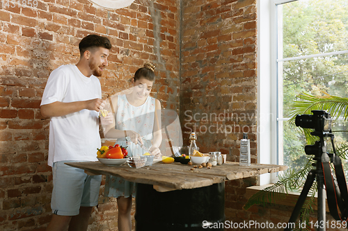 Image of Young couple cooking and recording live video for vlog and social media