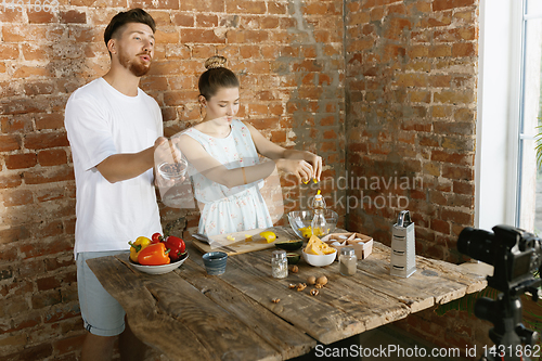 Image of Young couple cooking and recording live video for vlog and social media