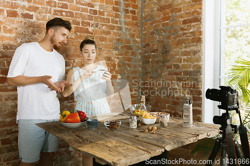 Image of Young couple cooking and recording live video for vlog and social media