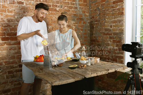 Image of Young couple cooking and recording live video for vlog and social media
