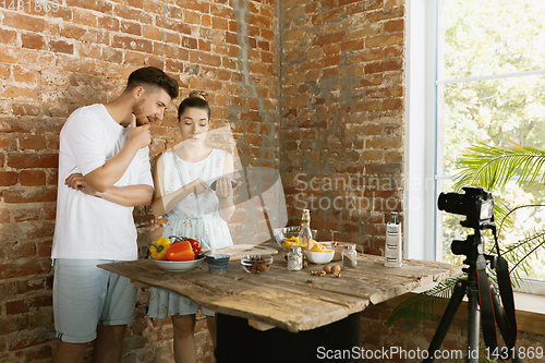 Image of Young couple cooking and recording live video for vlog and social media
