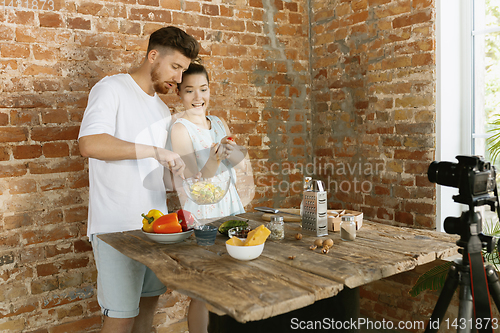 Image of Young couple cooking and recording live video for vlog and social media