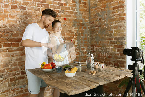 Image of Young couple cooking and recording live video for vlog and social media