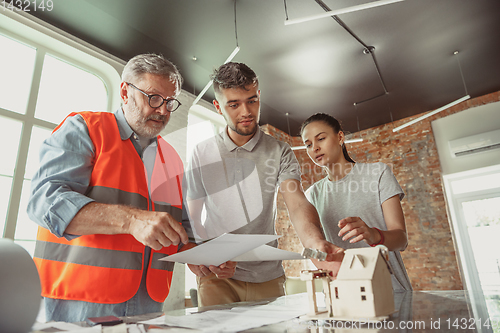 Image of Foreman or achitect shows house, office or store design plans to a young couple