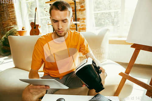 Image of Caucasian male blogger with camera recording video review of gadgets at home