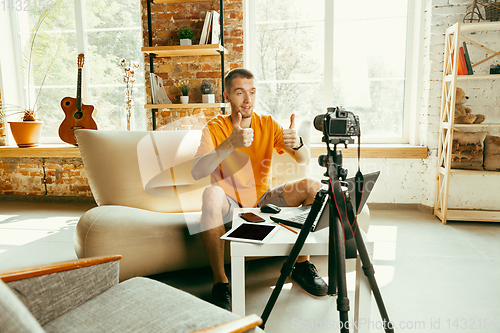 Image of Caucasian male blogger with camera recording video review of gadgets at home