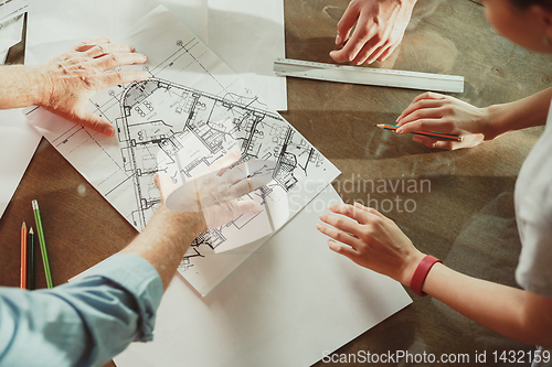 Image of Foreman or achitect shows house, office or store design plans to a young couple