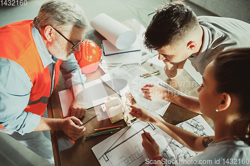 Image of Foreman or achitect shows house, office or store design plans to a young couple