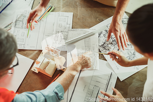 Image of Foreman or achitect shows house, office or store design plans to a young couple