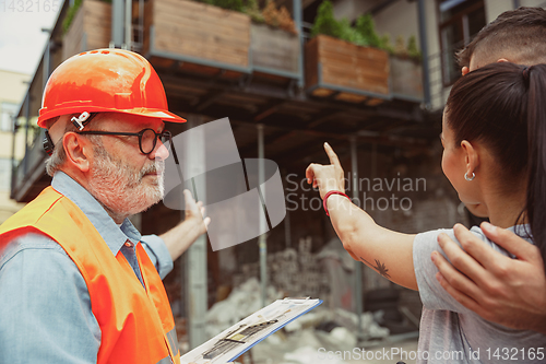 Image of Foreman or achitect shows house, office or store design plans to a young couple