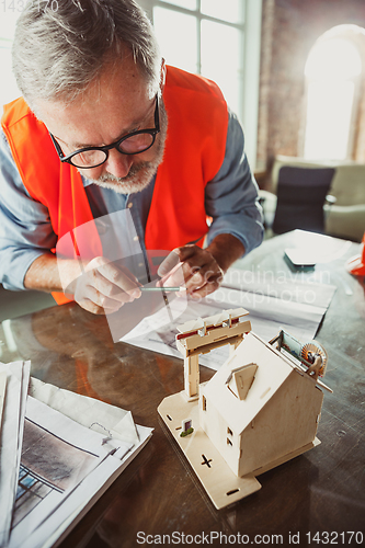 Image of Close up of male architect-engineer making a model of house