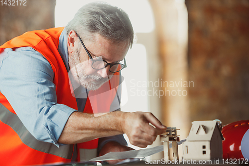 Image of Close up of male architect-engineer making a model of house