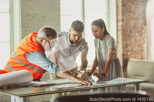 Image of Foreman or achitect shows house, office or store design plans to a young couple