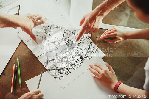 Image of Foreman or achitect shows house, office or store design plans to a young couple