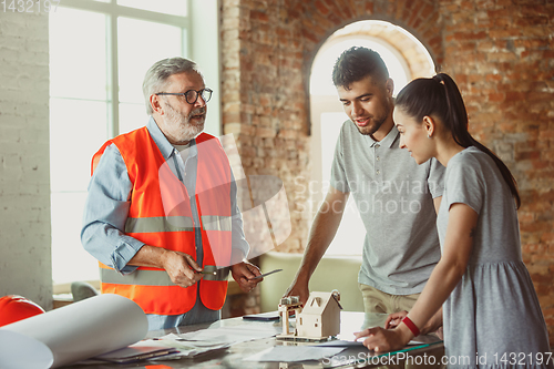 Image of Foreman or achitect shows house, office or store design plans to a young couple