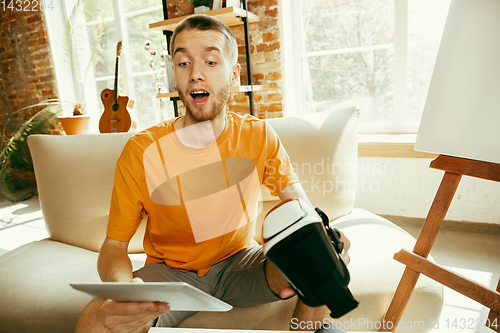 Image of Caucasian male blogger with camera recording video review of gadgets at home