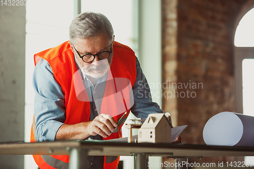 Image of Close up of male architect-engineer making a model of house