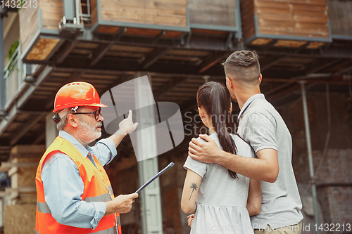 Image of Foreman or achitect shows house, office or store design plans to a young couple