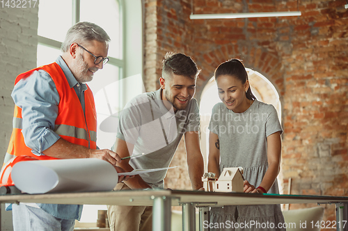 Image of Foreman or achitect shows house, office or store design plans to a young couple