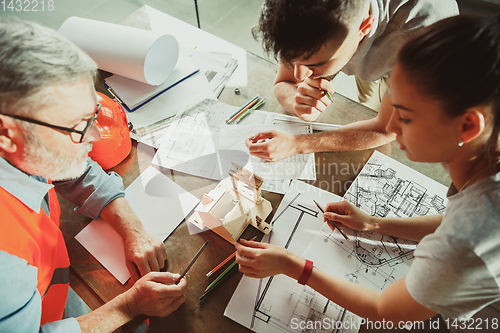 Image of Foreman or achitect shows house, office or store design plans to a young couple