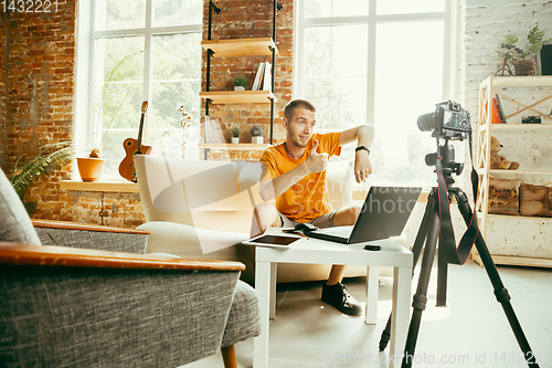 Image of Caucasian male blogger with camera recording video review of gadgets at home